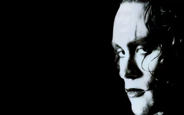 HD PC desktop wallpaper: dramatic close-up profile from the movie The Crow — a pale, painted face with dark eye makeup set against a deep black background.