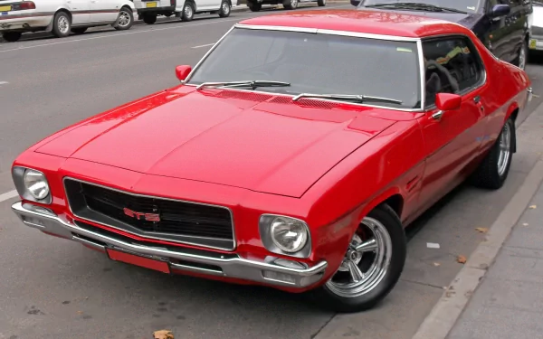 HD PC desktop wallpaper featuring a classic red Holden GTS vehicle parked on a city street.
