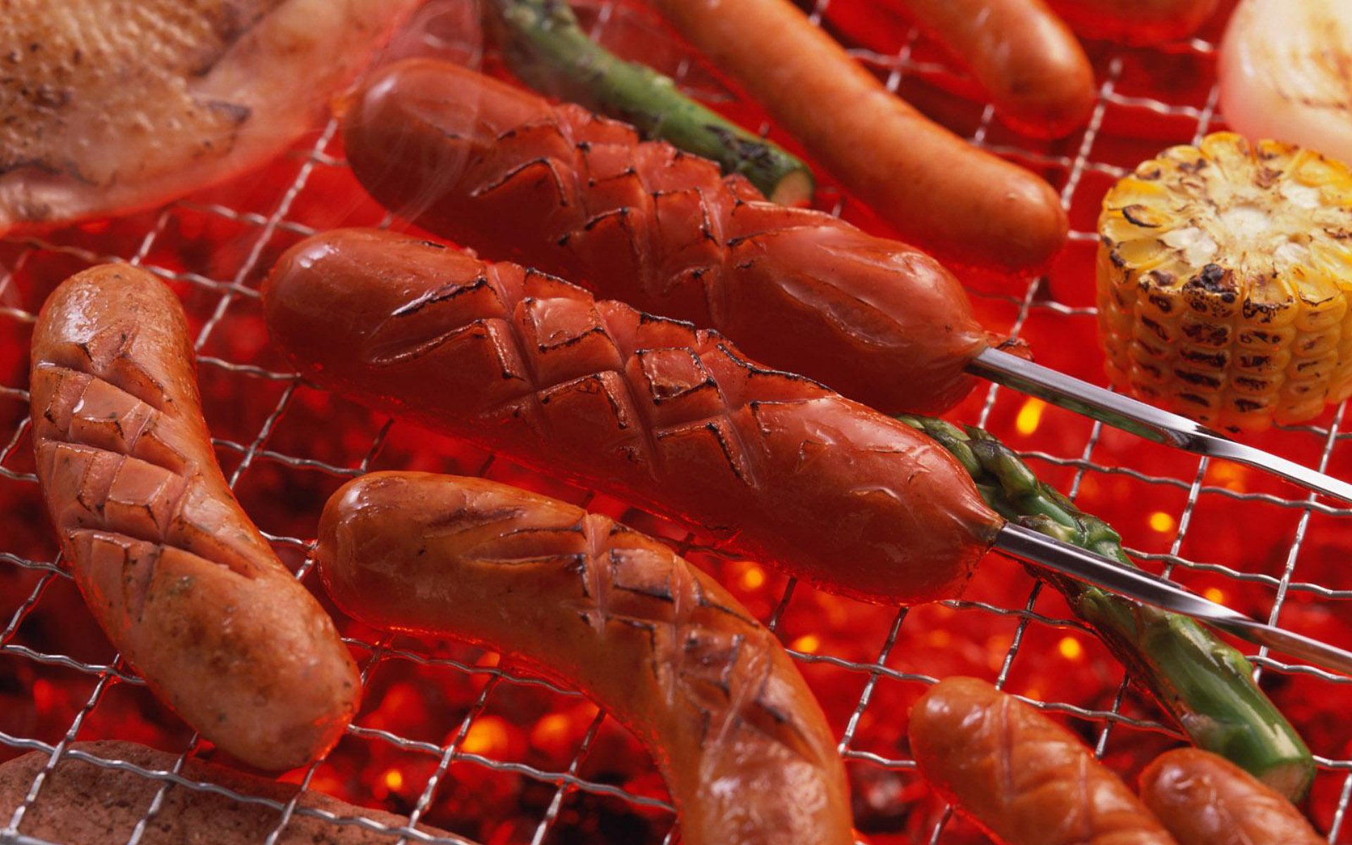HD PC desktop wallpaper featuring sizzling sausages, corn, and green peppers grilling over hot barbecue coals, highlighting food and barbecue themes.