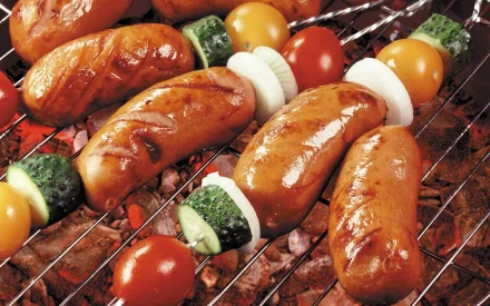 HD PC desktop wallpaper featuring juicy sausages and colorful vegetable skewers grilling on a barbecue, capturing rich food textures and vibrant colors.