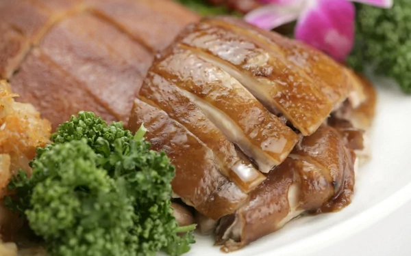 Close-up HD desktop wallpaper of sliced roasted Chinese duck garnished with parsley and a pink flower, showcasing rich textures and vibrant colors.