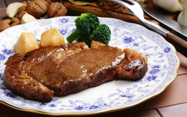 HD desktop wallpaper featuring a juicy barbecue steak served with broccoli and potatoes on a decorative blue and white plate.
