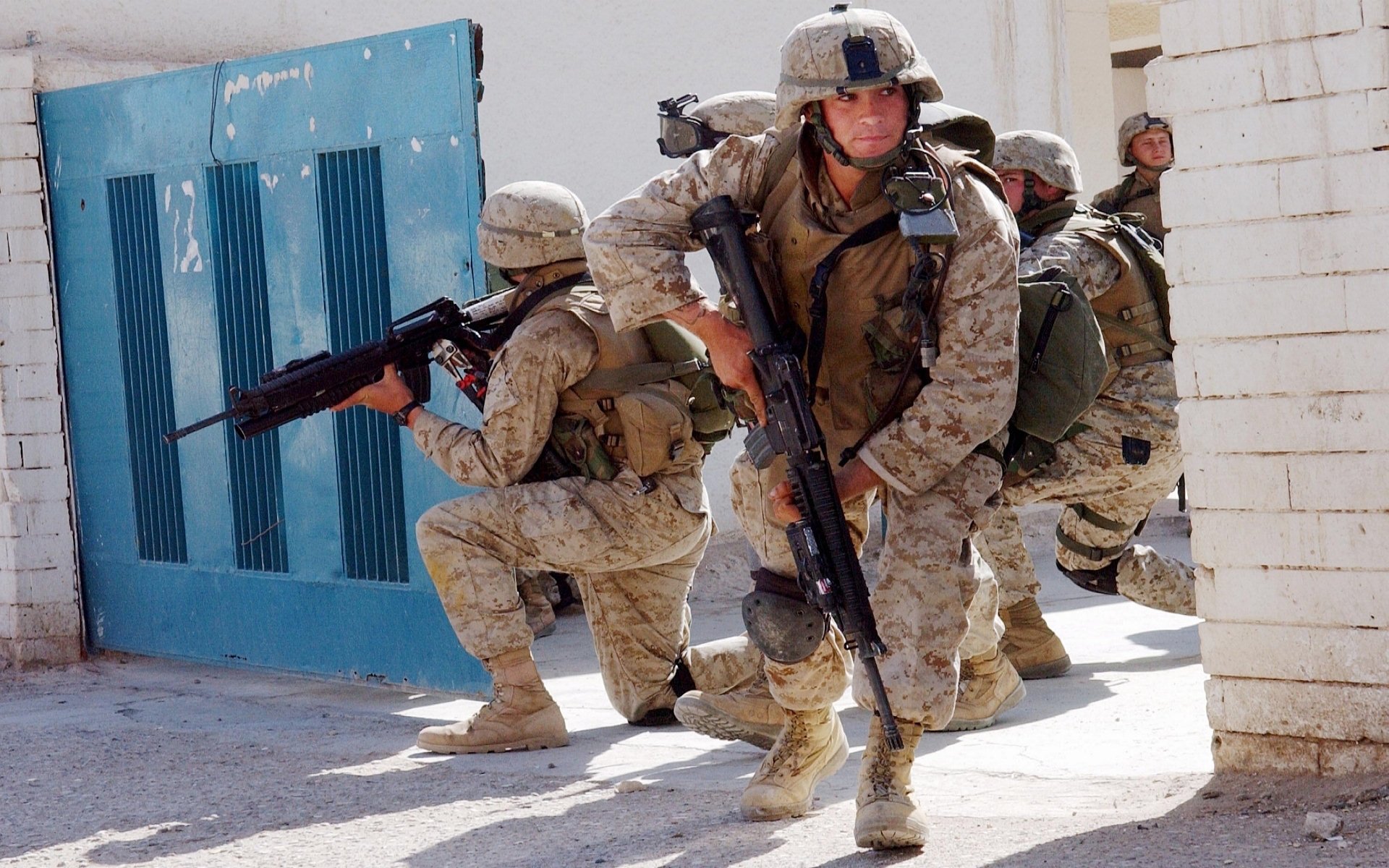 U.S. Army Infantry soldiers in full military gear armed with guns, positioned tactically during a combat operation, captured in HD for a desktop wallpaper background.