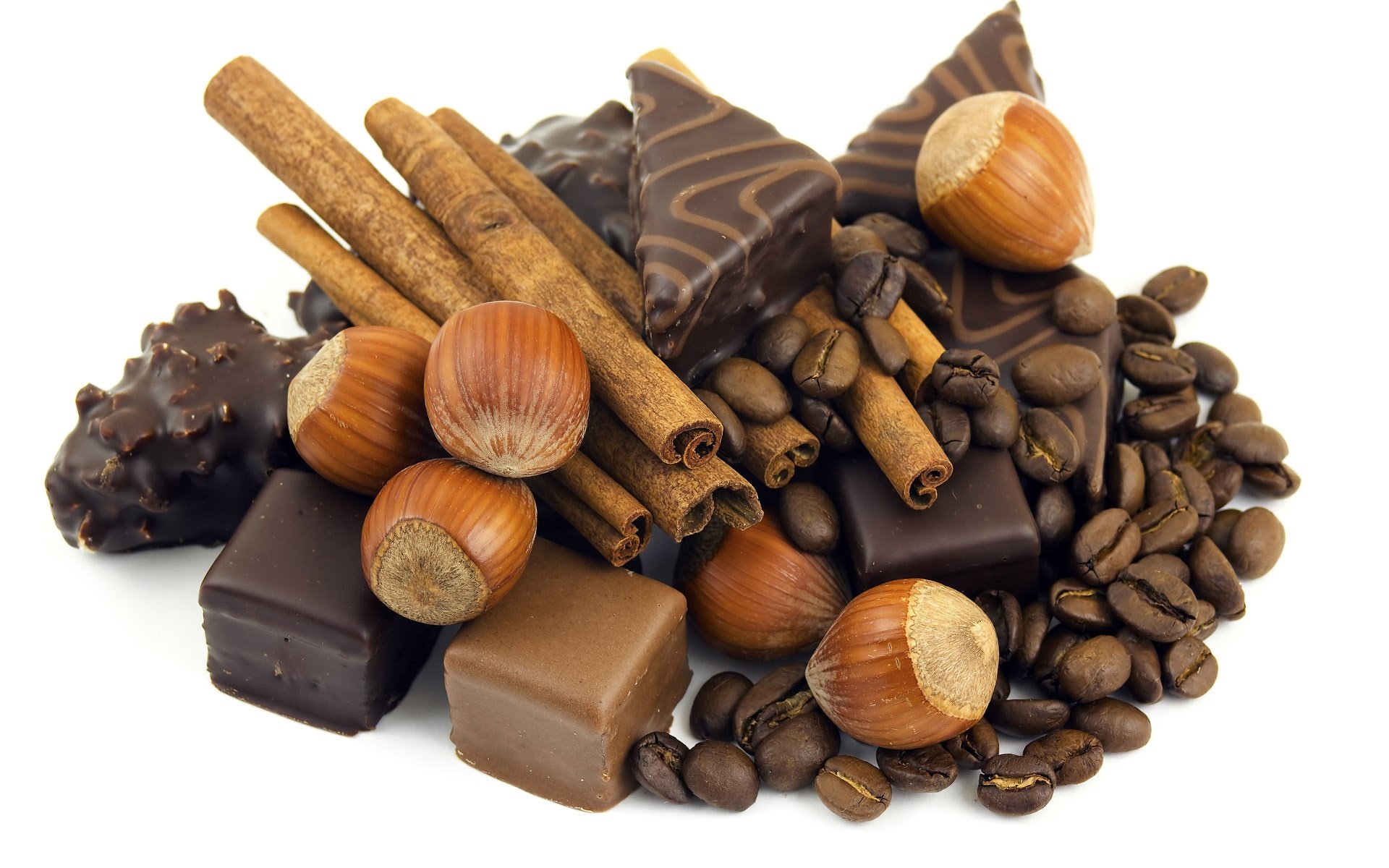 HD PC desktop wallpaper featuring assorted chocolate pieces, hazelnuts, cinnamon sticks, and coffee beans arranged on a white background.
