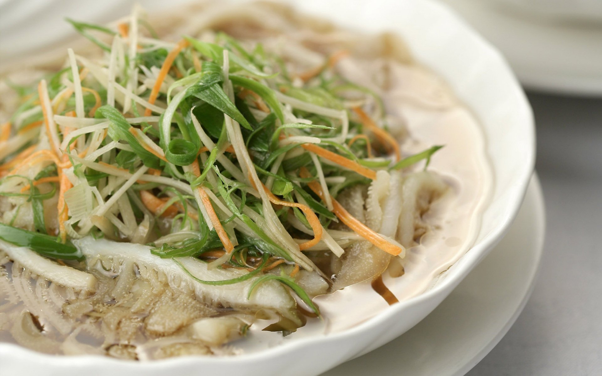 HD desktop wallpaper showing a close-up of a Chinese food dish with thinly sliced meat topped with shredded green onions and carrots on a white plate.