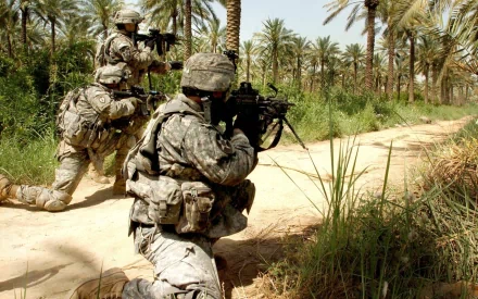 U.S. Army Infantry soldiers in full military gear wielding guns, advancing tactically through a palm-filled desert environment, captured in HD for a war-themed desktop wallpaper.