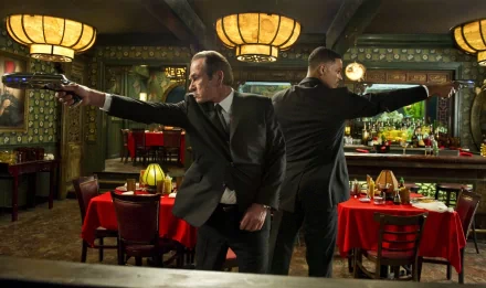 HD PC desktop wallpaper featuring a scene from the movie Men In Black 3 with two agents in black suits aiming guns inside a retro-styled restaurant.