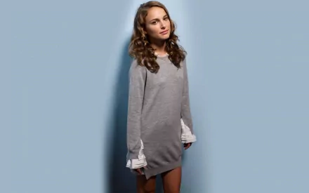 A high-definition desktop wallpaper featuring Natalie Portman, showcasing her elegant style in a gray outfit with a light blue background.