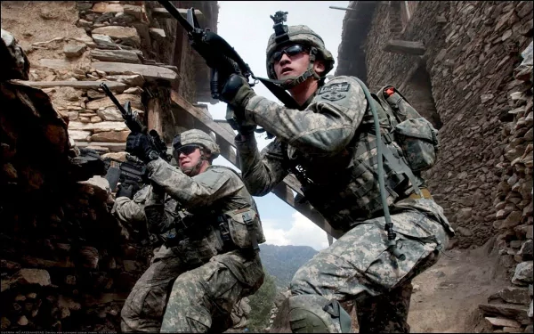 HD desktop wallpaper depicting U.S. Army infantry soldiers armed and advancing through a narrow, war-torn urban environment, showcasing military action and weaponry.