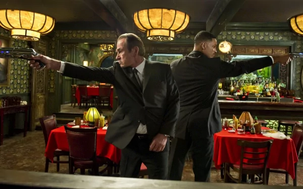 HD PC desktop wallpaper featuring a scene from the movie Men In Black 3 with two agents in black suits aiming guns inside a retro-styled restaurant.