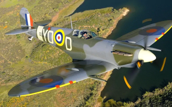HD desktop wallpaper featuring a Supermarine Spitfire military aircraft flying over a river and green landscape in bright daylight.
