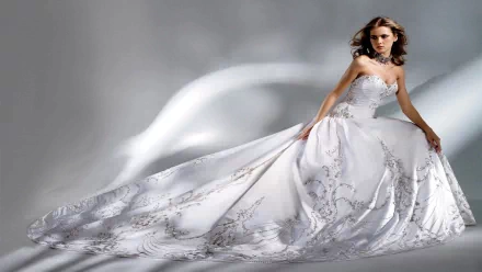 A stunning bride in an elegant white gown poses gracefully against a soft, flowing background, creating an enchanting HD desktop wallpaper.