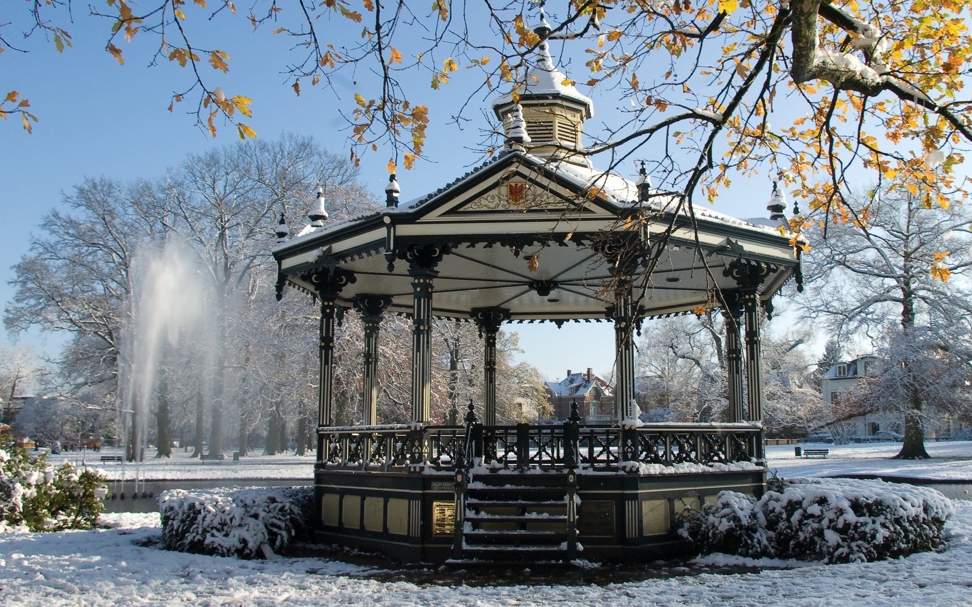 HD PC desktop wallpaper featuring a man-made ornate gazebo surrounded by snow-covered ground and trees, with a fountain and clear sky in the background.