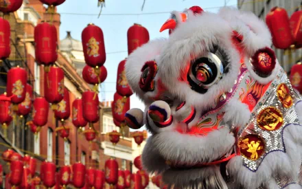 HD PC desktop wallpaper depicting a vibrant Chinese New Year celebration with a traditional lion dance costume amidst hanging red lanterns.