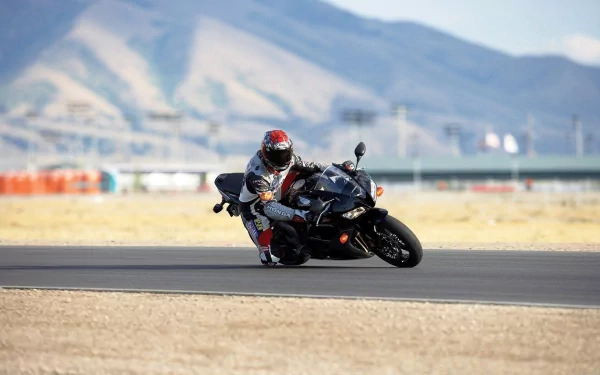 A high-definition MotoGP desktop wallpaper featuring a rider leaning into a turn on a motorcycle against a mountainous background.