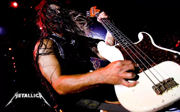 A dynamic shot of a bassist performing on stage, emphasizing intense energy and movement, surrounded by vibrant concert lights, with the Metallica logo featured prominently.