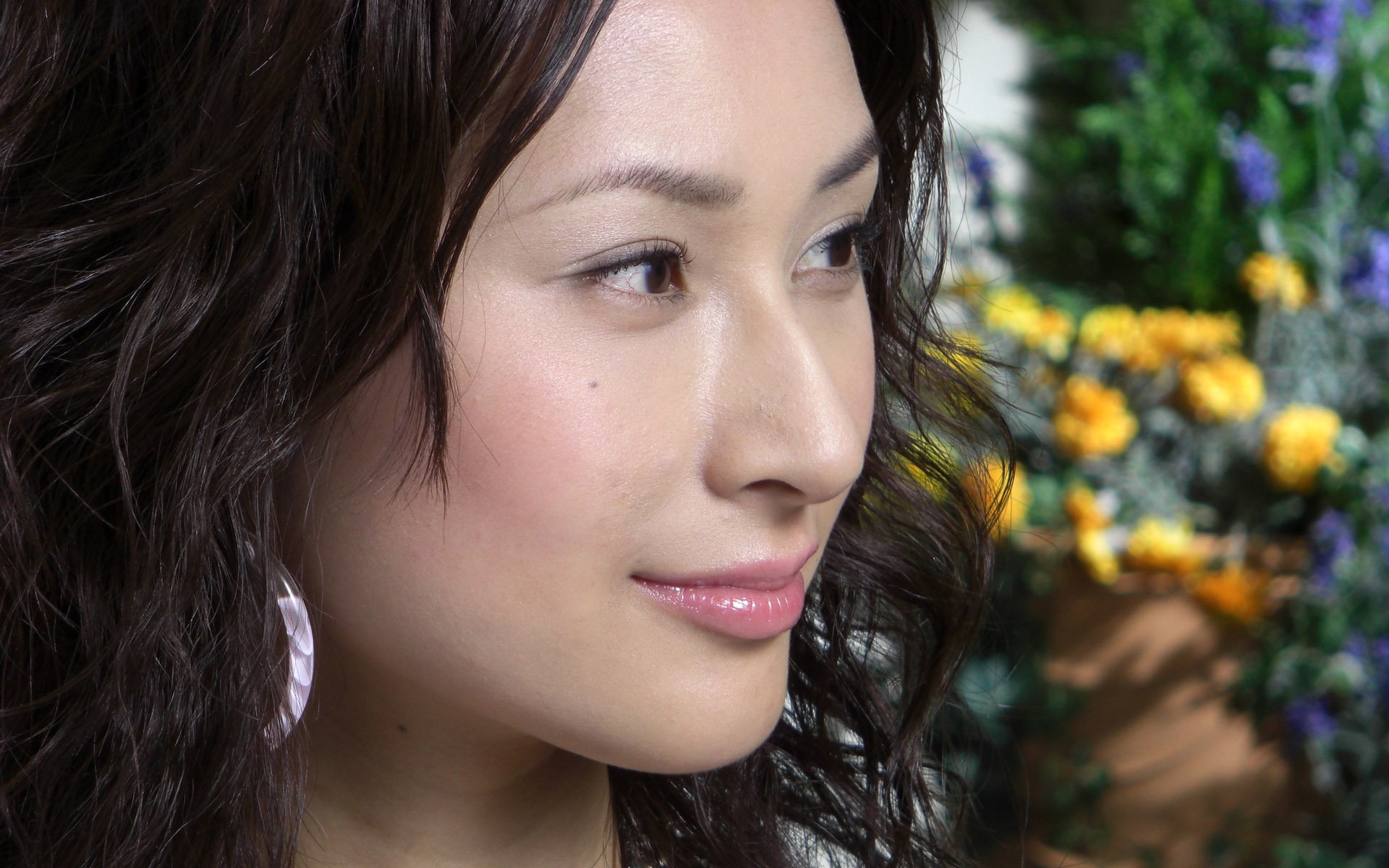 HD PC desktop wallpaper: close-up profile of an Asian woman with wavy hair, subtle makeup, and a blurred floral background.