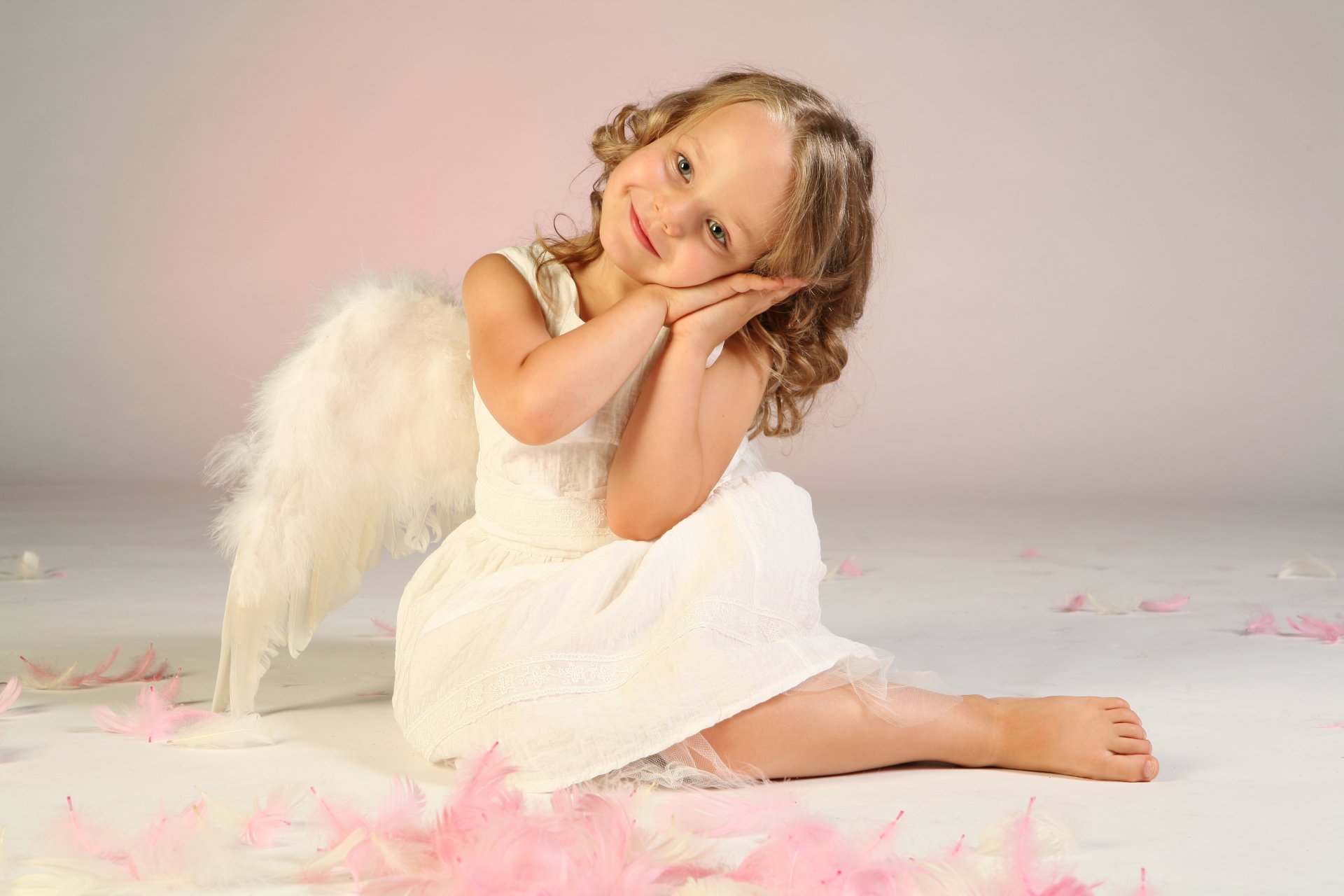 Photography, child — a child in a white dress and angel wings seated among pink feathers on a soft studio backdrop; 4K Ultra HD PC desktop wallpaper/background.