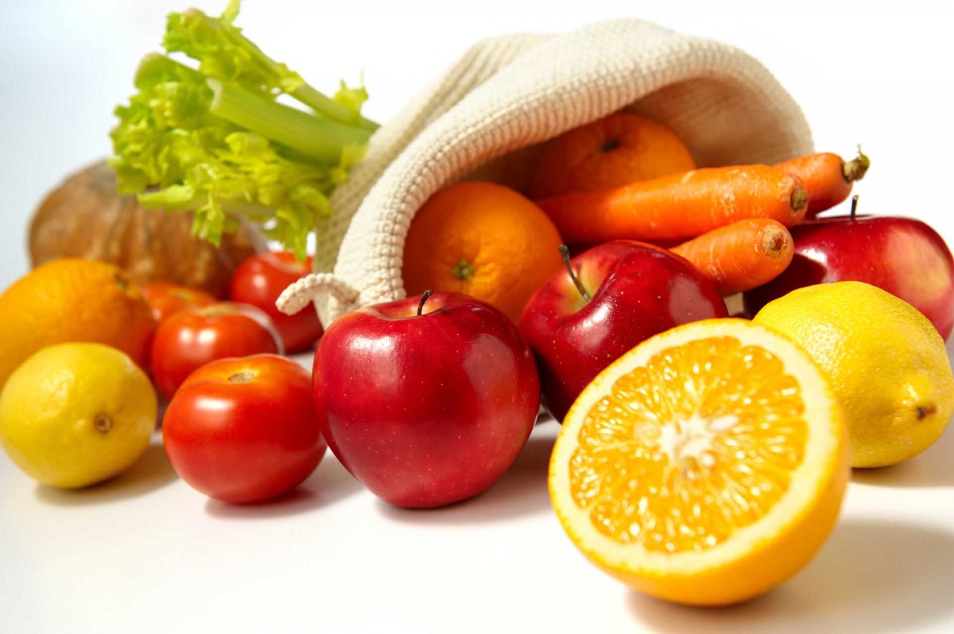 HD PC desktop wallpaper featuring a vibrant assortment of fresh fruits and vegetables spilling from a cloth bag on a white background.