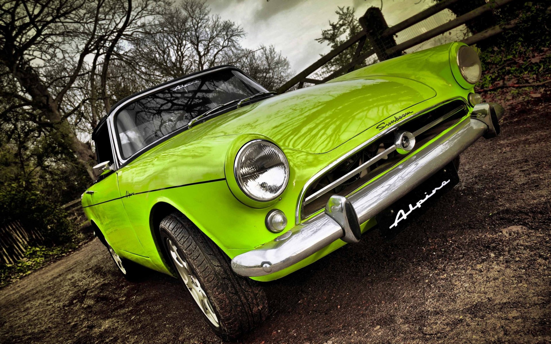 Low-angle shot of a lime-green Sunbeam Alpine convertible on a country lane, high-contrast 2K Quad HD PC desktop wallpaper/background.