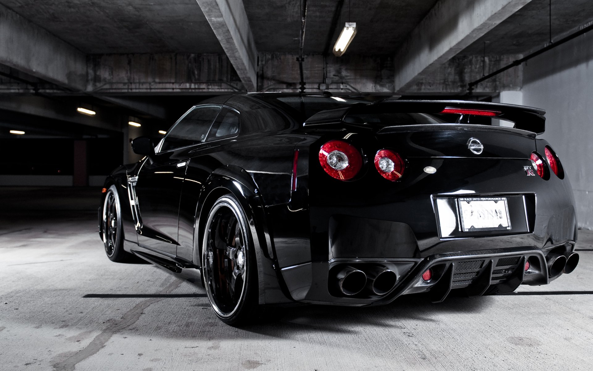 HD desktop wallpaper of a sleek black Nissan vehicle parked in a dimly lit underground garage, showcasing its sporty rear design and glossy finish.