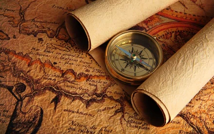 An HD wallpaper featuring vintage maps, with rolled parchment and a brass compass resting atop intricate cartographic details, creating an adventurous and nostalgic ambiance.