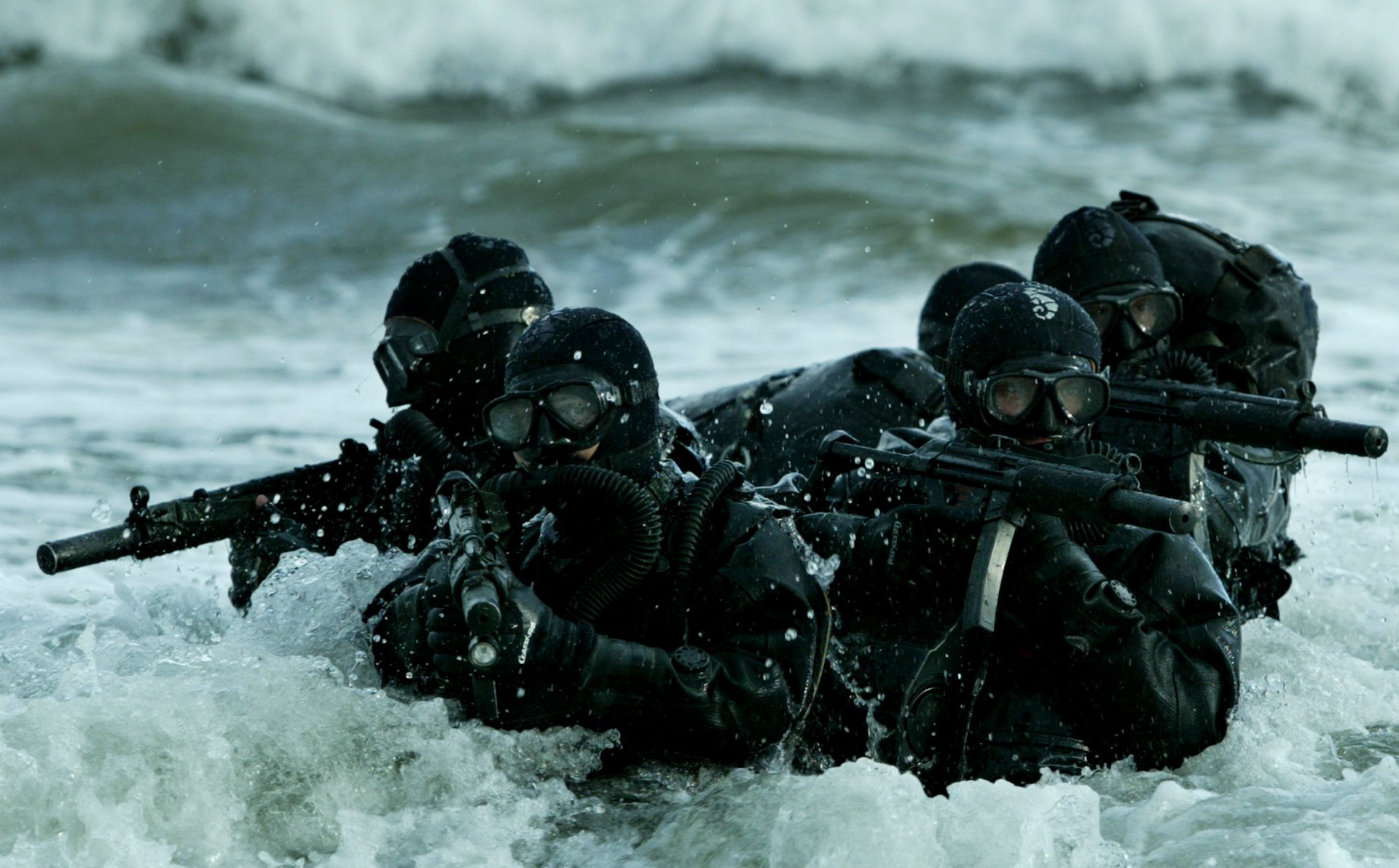 A group of soldiers in tactical gear wading through ocean waves, showcasing a strong military presence. This HD wallpaper captures the intensity of a military operation.