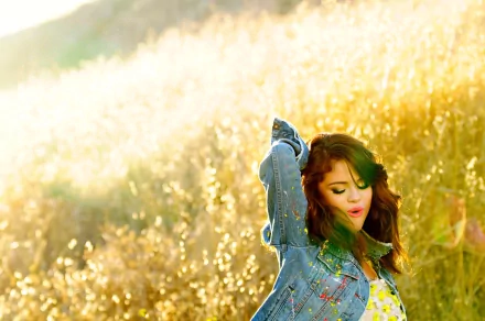 A vibrant HD desktop wallpaper featuring Selena Gomez dancing joyfully in a sunlit field, surrounded by golden grass, embodying a carefree and musical spirit.
