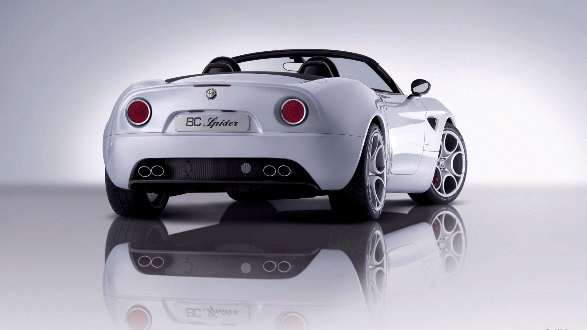 Rear three-quarter view of a silver Alfa Romeo 8C Spider sports car on a glossy reflective surface — HD PC desktop wallpaper/background.