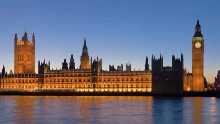 HD image of London featuring the illuminated Big Ben and Houses of Parliament at dusk, reflecting beautifully off the River Thames.