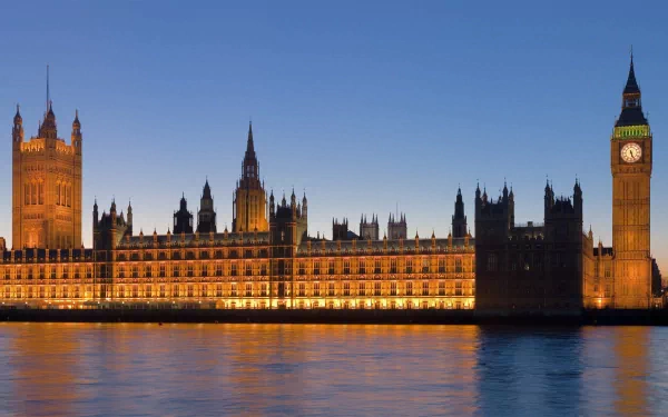 HD image of London featuring the illuminated Big Ben and Houses of Parliament at dusk, reflecting beautifully off the River Thames.