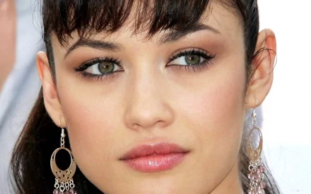 HD PC desktop wallpaper featuring a close-up portrait of celebrity Olga Kurylenko with striking eyes and elegant earrings.