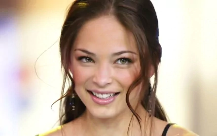 HD PC desktop wallpaper featuring a close-up of celebrity Kristin Kreuk smiling with soft lighting and a blurred background.