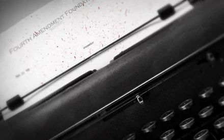 Close-up HD desktop wallpaper of a vintage typewriter with a typed sheet showing Fourth Amendment Foundation text on a white background.
