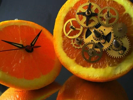 HD wallpaper of a sliced orange, one half with clock hands and the other half filled with clockwork gears. Tags: fruit, food, orange, clockwork.