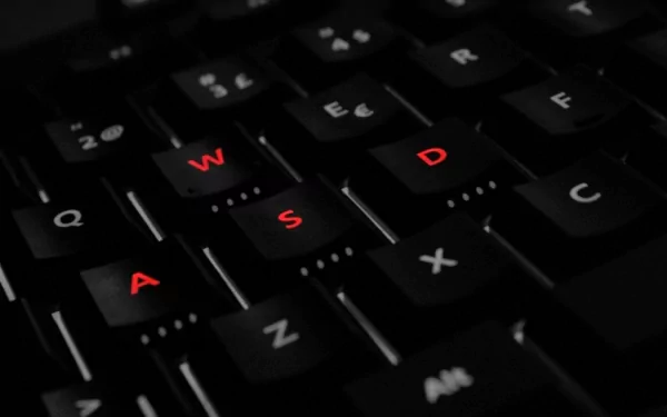 Close-up HD image of a black computer keyboard with the keys W, A, S, and D highlighted in red, reflecting a technology-themed desktop wallpaper and background.