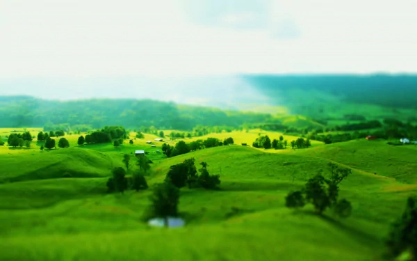 Tilt-shift landscape photography of vivid green rolling hills, scattered trees and ponds — 4K Ultra HD PC desktop wallpaper/background.