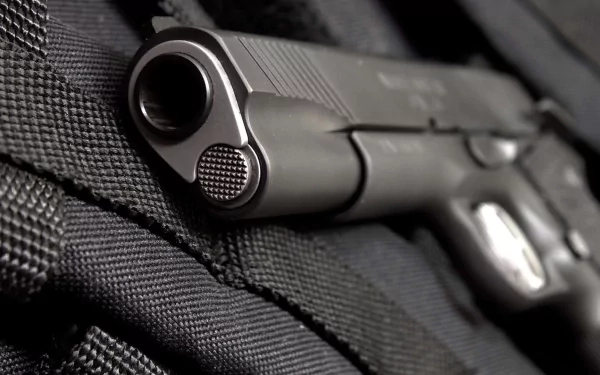A close-up view of a Colt 1911 handgun set against a textured black background, showcasing its sleek design and craftsmanship in high-definition.