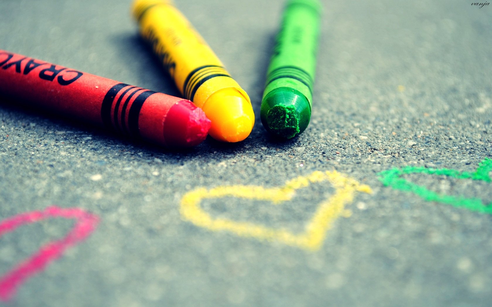 Artistic HD desktop wallpaper featuring red, yellow, and green crayons drawing colorful hearts on a textured surface, conveying a theme of love.