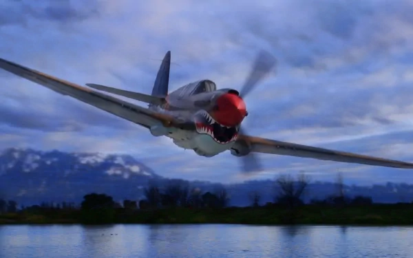 HD PC desktop wallpaper featuring a military aircraft in flight over a reflective body of water with mountains and a cloudy sky in the background.