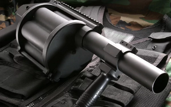 HD PC desktop wallpaper: close-up of a military rocket launcher on a tactical vest, matte metal barrel and revolving cylinder in sharp focus against a subdued camouflage background.