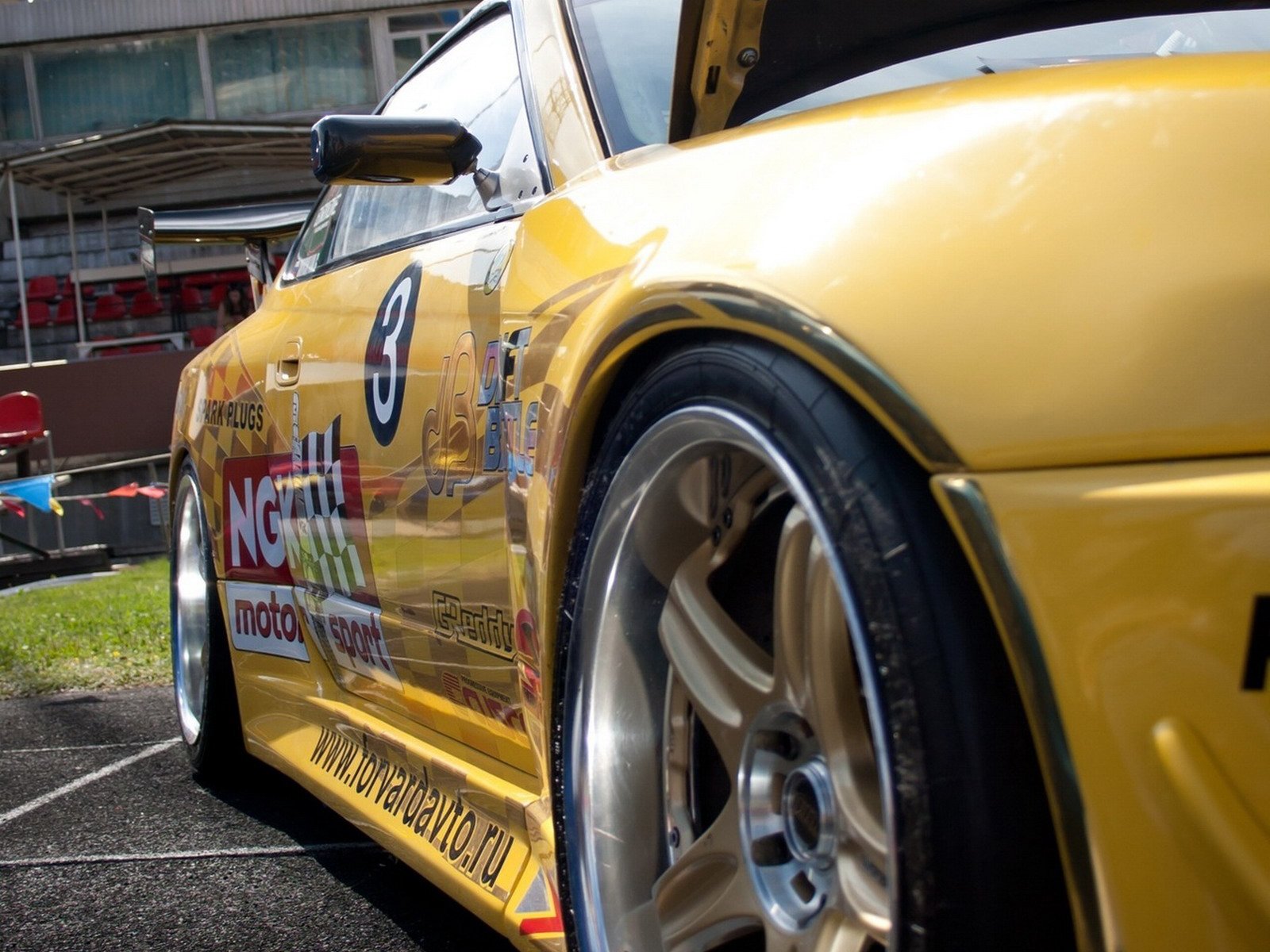 Close-up of a yellow sports car (vehicle) rear wheel and fender with race decals — HD PC desktop wallpaper and background