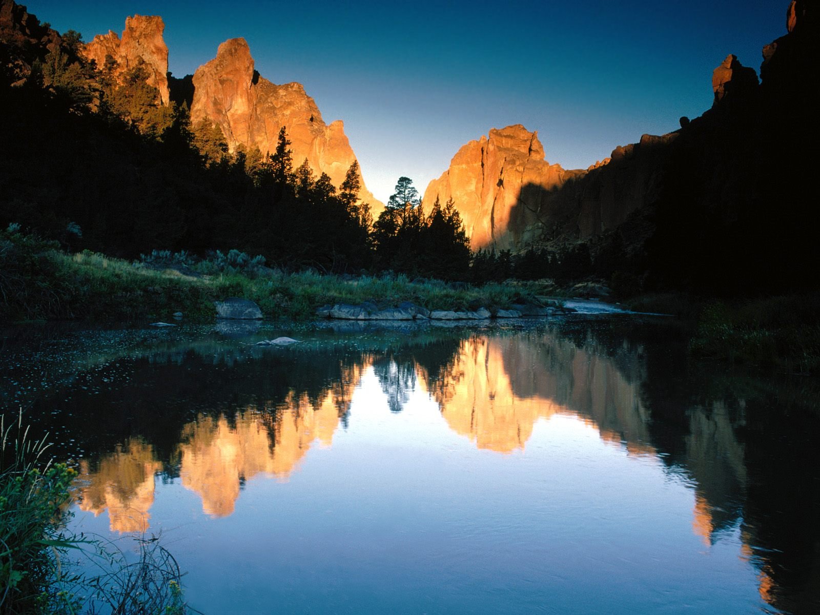HD desktop wallpaper featuring a serene lake with a clear reflection of surrounding mountains at sunset, highlighting the beauty of nature.