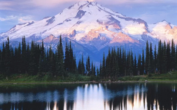 A stunning HD wallpaper featuring a serene lake reflecting a snow-capped mountain, surrounded by a dense forest, with nature’s beauty on full display.