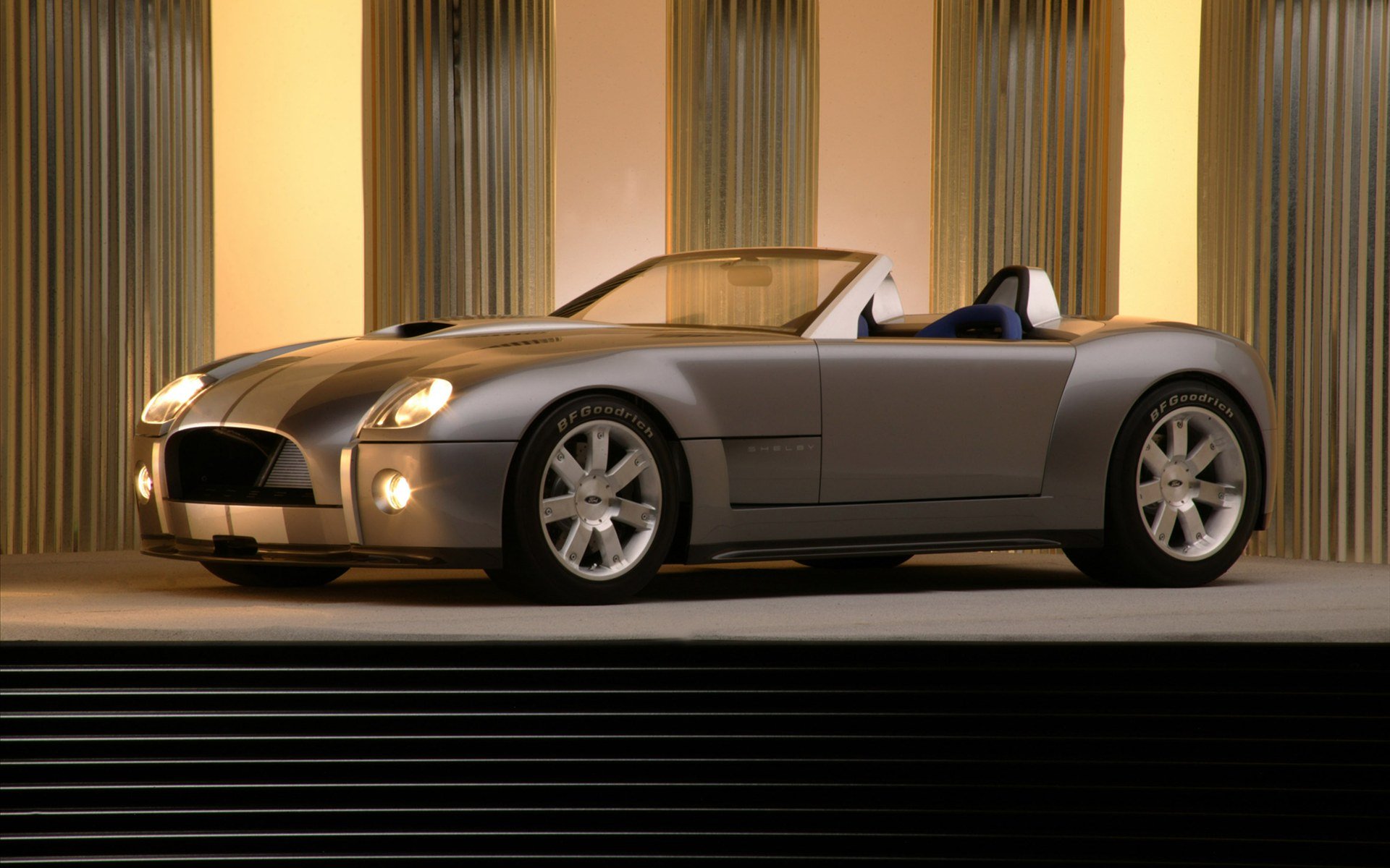 HD PC desktop wallpaper/background: silver AC Cobra vehicle on a lit stage with warm vertical curtains, low-angle profile view.