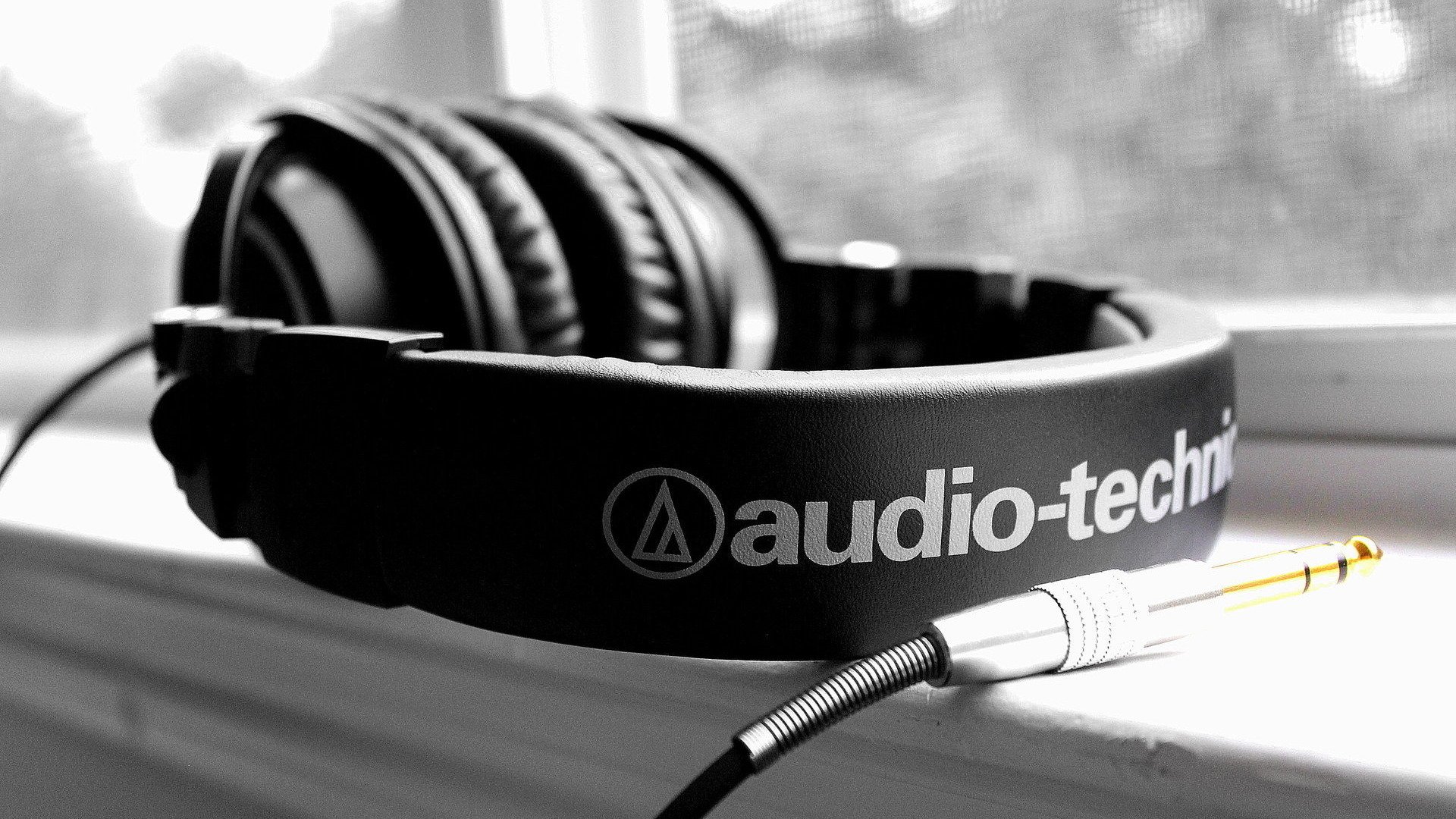 Black Audio-Technica headphones rest on a windowsill in a sharp black-and-white HD PC desktop wallpaper focused on music and audio equipment.
