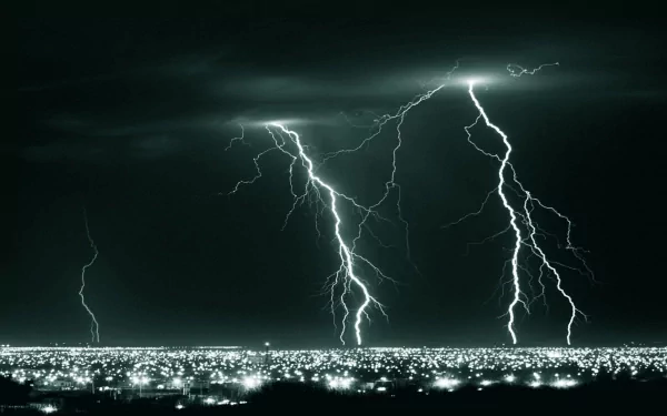A dramatic black-and-white photograph showcasing powerful lightning strikes illuminating a vibrant cityscape at night, serving as an HD desktop wallpaper and background.