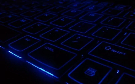 Close-up HD desktop wallpaper of a backlit keyboard with glowing blue keys, highlighting technology and modern computer design.