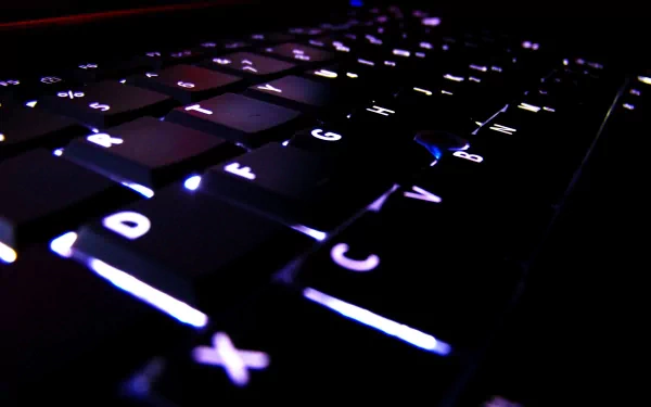 Close-up HD desktop wallpaper of a backlit Dell keyboard highlighting technology with glowing keys in low light.
