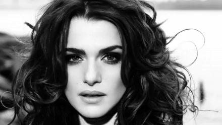 Black and white close-up portrait of celebrity Rachel Weisz, featuring her wavy dark hair and intense gaze. This HD desktop wallpaper and background captures her striking beauty.